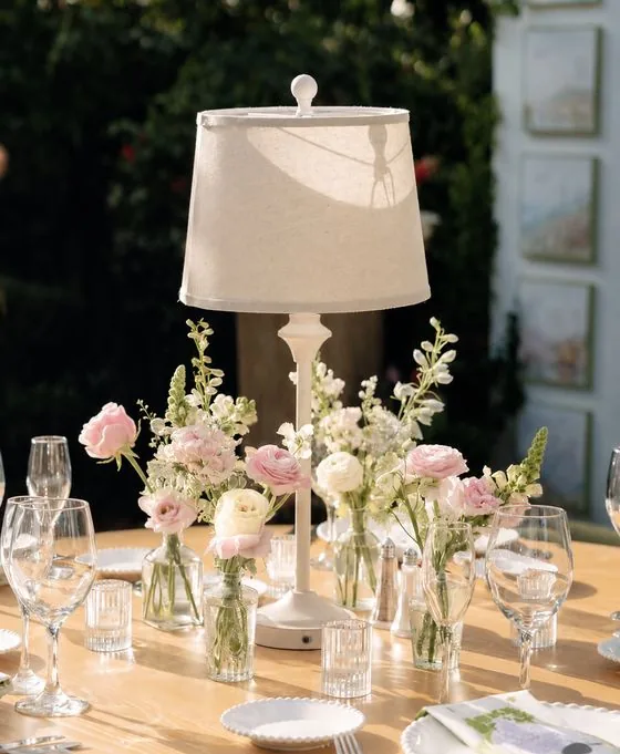 Centre de table : fioles de roses poudrées et lanterne blanche, table en extérieur