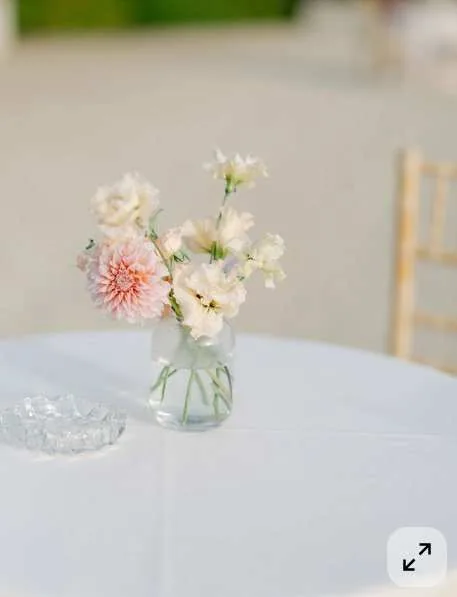 Mange-debout : fiole de fleurs poudrées sur table ronde habillée
