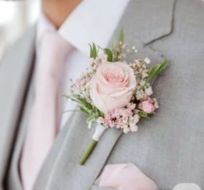 Boutonnière du marié : rose poudrée et gypsophile sur costume gris